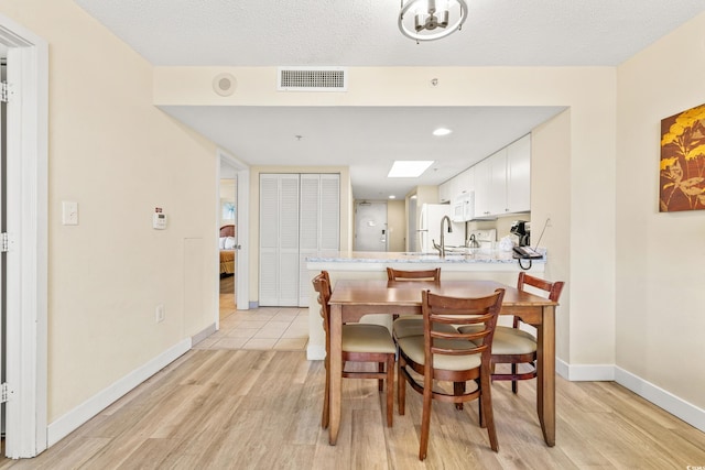 dining space featuring light hardwood / wood-style flooring and a textured ceiling