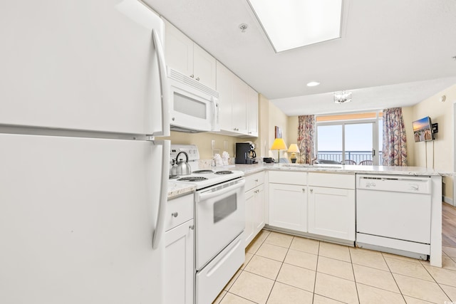 kitchen featuring white appliances, white cabinetry, light tile patterned floors, and kitchen peninsula