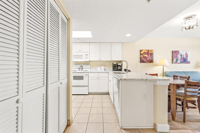 kitchen featuring light tile patterned floors, kitchen peninsula, sink, white appliances, and white cabinetry