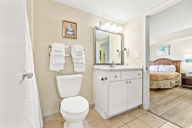 bathroom with a textured ceiling, vanity, toilet, and tile patterned floors