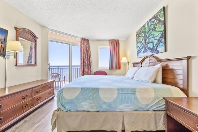 bedroom featuring a textured ceiling, access to outside, and light hardwood / wood-style flooring