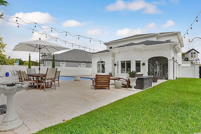 rear view of property with a lawn, outdoor lounge area, and a patio