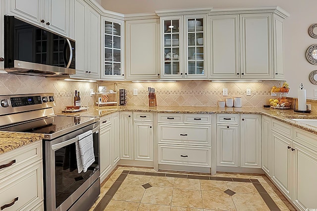 kitchen with tasteful backsplash, white cabinetry, light stone counters, and stainless steel appliances