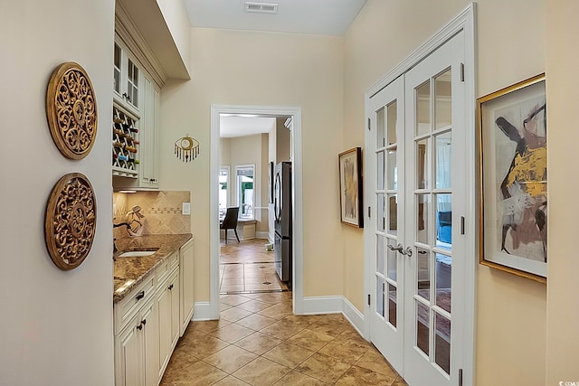 interior space with light tile patterned floors, sink, and french doors