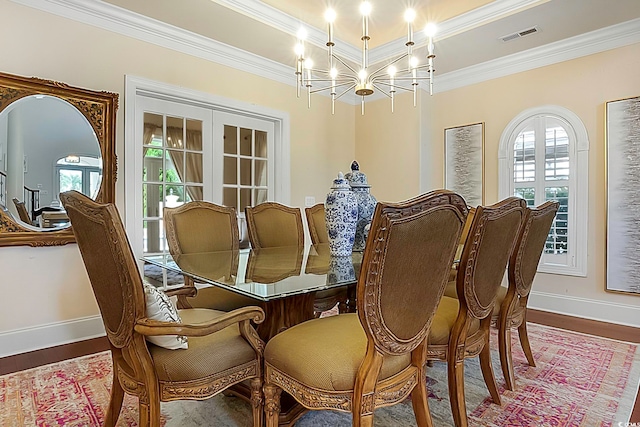 dining space featuring hardwood / wood-style floors, crown molding, and a notable chandelier