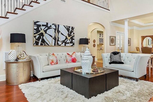 living room with a high ceiling, dark hardwood / wood-style flooring, and ornamental molding