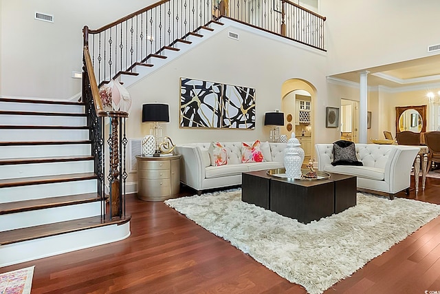 living room with ornamental molding, a notable chandelier, dark hardwood / wood-style floors, and a high ceiling