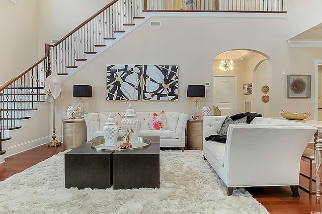 living room with a high ceiling, crown molding, and dark hardwood / wood-style flooring