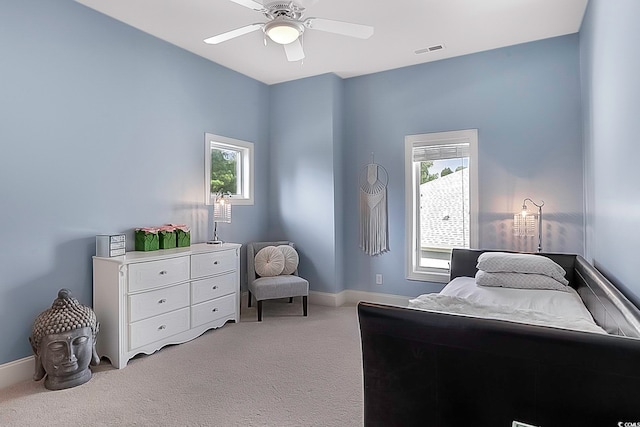 bedroom with light colored carpet, multiple windows, and ceiling fan