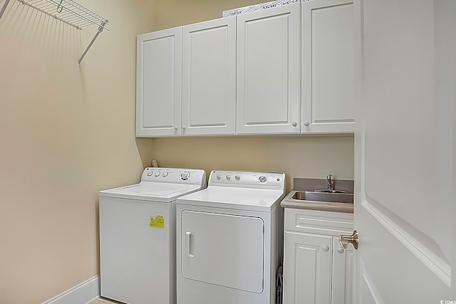 washroom with sink, cabinets, and washing machine and clothes dryer