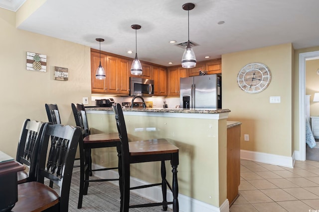 kitchen featuring dark stone counters, decorative light fixtures, appliances with stainless steel finishes, and kitchen peninsula