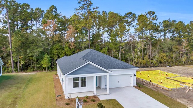 view of front of property featuring concrete driveway, a front yard, a garage, and roof with shingles