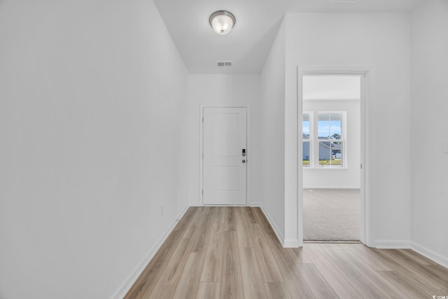 hall featuring baseboards, visible vents, and light wood-style flooring