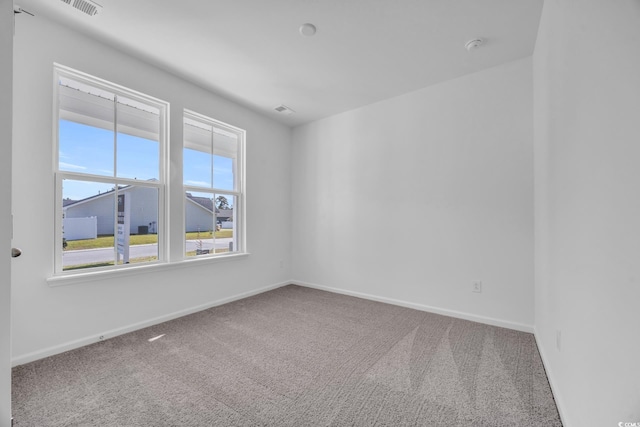 carpeted empty room featuring baseboards and visible vents