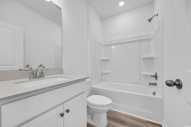 full bath with tub / shower combination, toilet, vanity, and wood finished floors