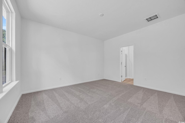 carpeted spare room featuring baseboards and visible vents