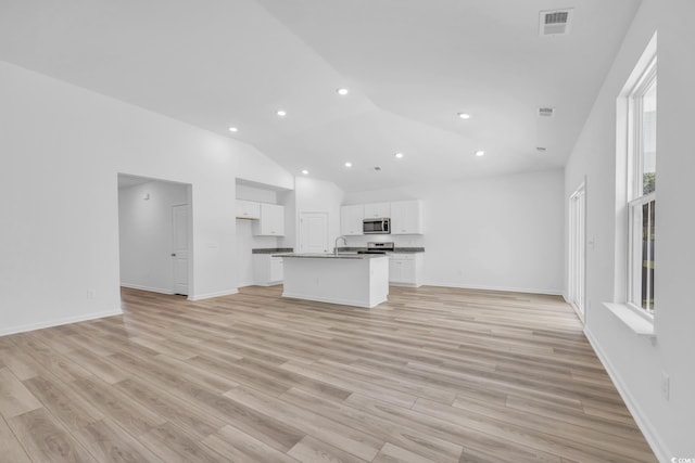 unfurnished living room featuring high vaulted ceiling, light hardwood / wood-style flooring, and sink