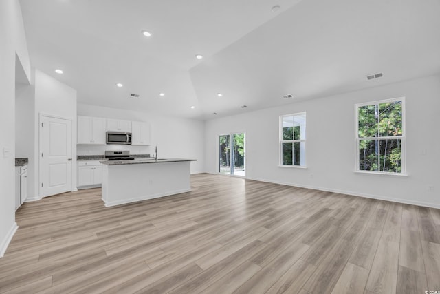 kitchen with light hardwood / wood-style flooring, white cabinets, appliances with stainless steel finishes, and plenty of natural light