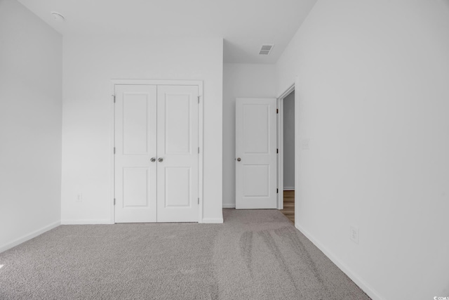 unfurnished bedroom with light carpet and a closet