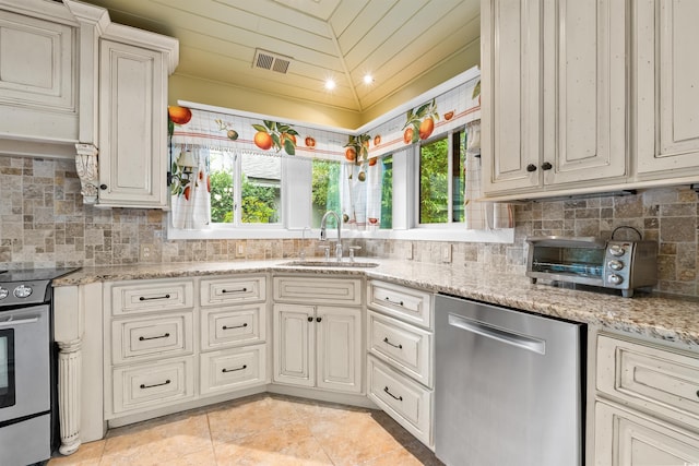 kitchen with tasteful backsplash, sink, stainless steel appliances, vaulted ceiling, and light stone counters