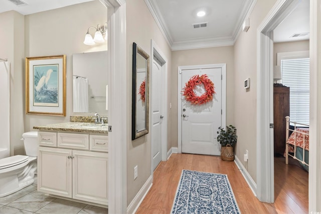 doorway to outside featuring ornamental molding, light hardwood / wood-style floors, and sink