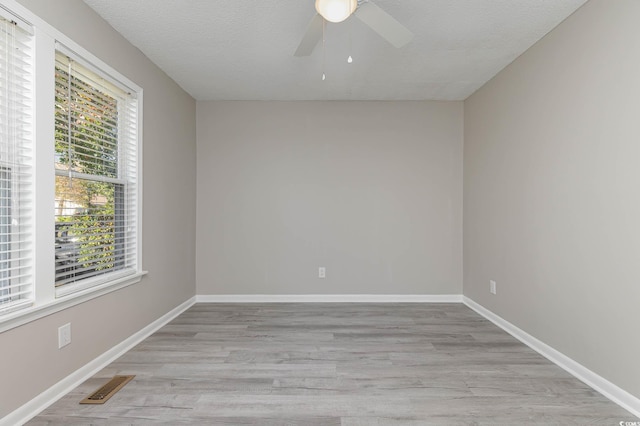 unfurnished room featuring a wealth of natural light, a textured ceiling, light wood-type flooring, and ceiling fan