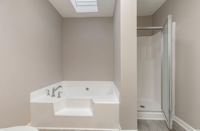 bathroom featuring hardwood / wood-style floors, shower with separate bathtub, and a skylight