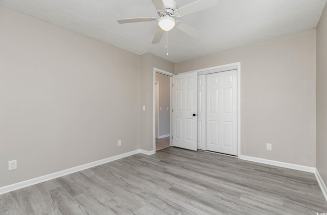 unfurnished bedroom featuring a closet, ceiling fan, a textured ceiling, and light wood-type flooring