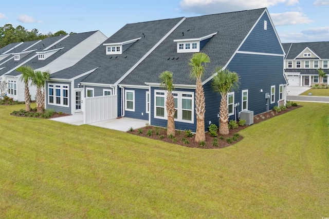 rear view of property with a lawn, cooling unit, and a garage