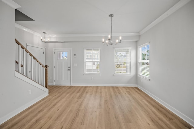 foyer entrance with ornamental molding, a chandelier, and light hardwood / wood-style floors