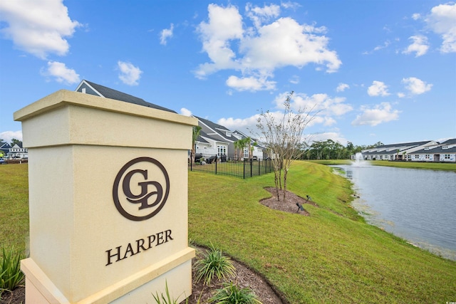 community sign with a lawn and a water view