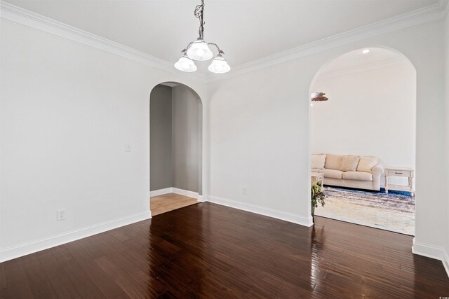 empty room with hardwood / wood-style floors, crown molding, and a chandelier