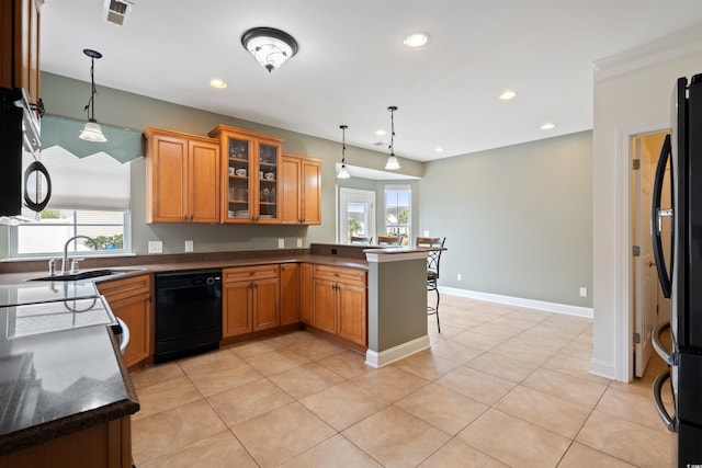 kitchen featuring black appliances, kitchen peninsula, a breakfast bar, sink, and decorative light fixtures