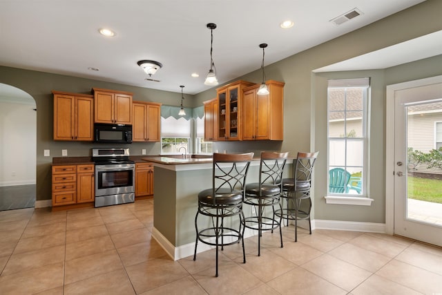 kitchen featuring stainless steel range with electric cooktop, decorative light fixtures, light tile patterned floors, kitchen peninsula, and a breakfast bar