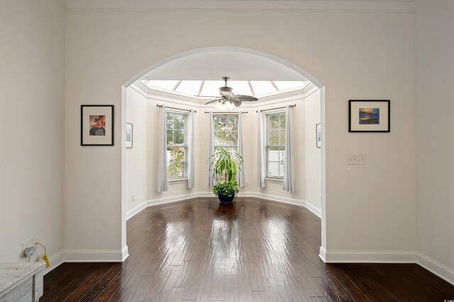 foyer entrance with dark wood-type flooring, ceiling fan, and ornamental molding