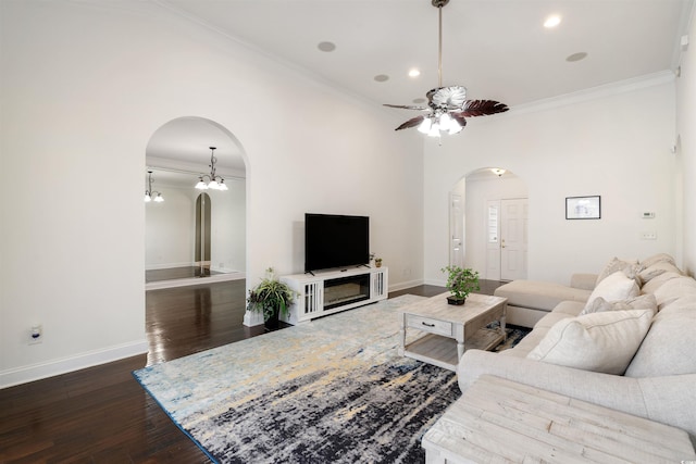 living room with ornamental molding, dark wood-type flooring, and ceiling fan with notable chandelier