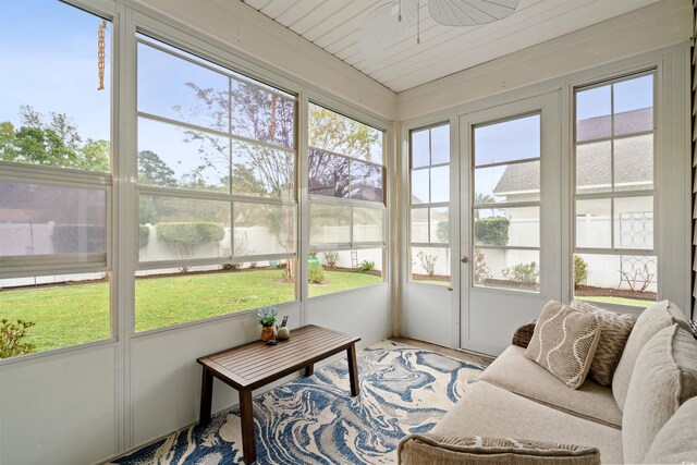 sunroom with ceiling fan and a water view