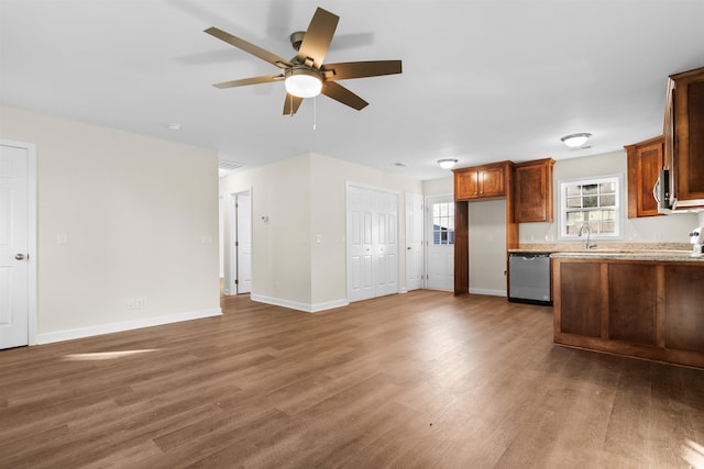 kitchen featuring hardwood / wood-style flooring, sink, appliances with stainless steel finishes, light stone counters, and ceiling fan