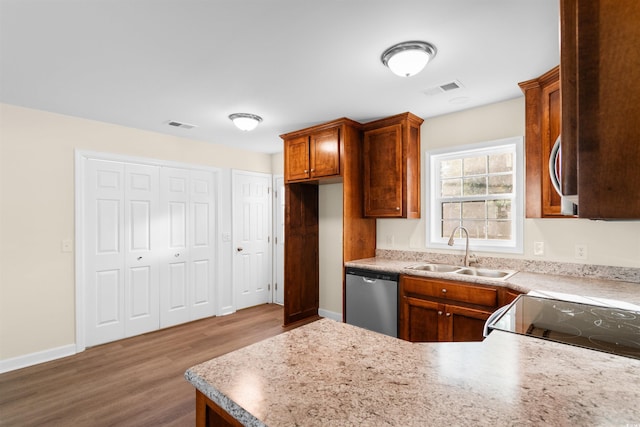 kitchen featuring stainless steel dishwasher, black range, hardwood / wood-style flooring, and sink