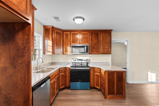 kitchen featuring light stone countertops, sink, appliances with stainless steel finishes, and light wood-type flooring