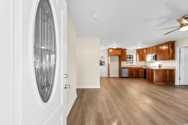 kitchen with light hardwood / wood-style floors, stainless steel appliances, sink, and ceiling fan