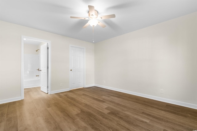 unfurnished bedroom featuring a closet, hardwood / wood-style floors, ensuite bathroom, and ceiling fan