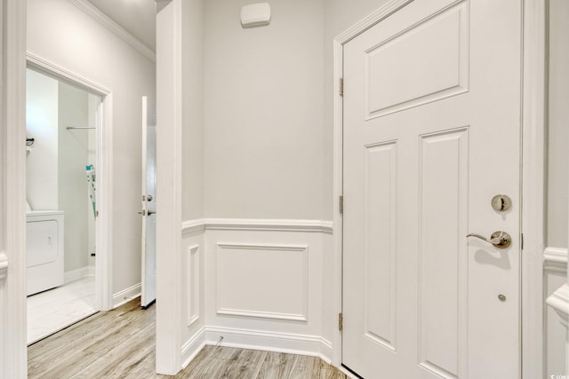 hallway with crown molding, washer / dryer, and light hardwood / wood-style floors