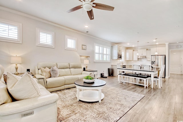 living room with crown molding, ceiling fan, and light wood-type flooring