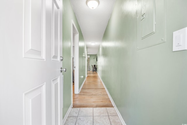 hall featuring light tile patterned flooring and a textured ceiling