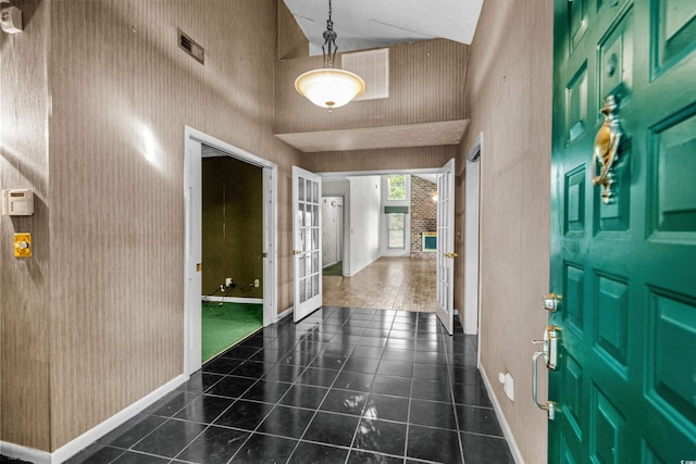 foyer entrance featuring tile patterned flooring, visible vents, a towering ceiling, baseboards, and french doors