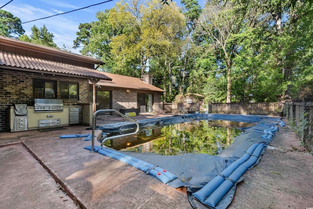 view of swimming pool featuring a fenced in pool, a patio area, exterior kitchen, and grilling area