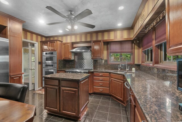 kitchen featuring backsplash, crown molding, appliances with stainless steel finishes, a sink, and wall chimney exhaust hood