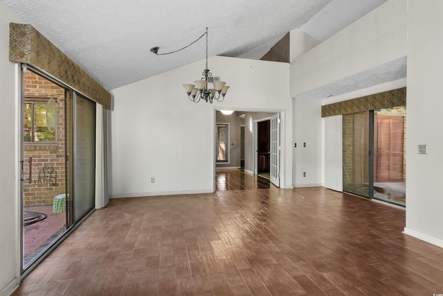 unfurnished dining area with baseboards, an inviting chandelier, wood finished floors, and high vaulted ceiling