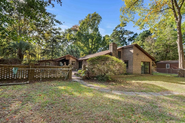 exterior space with brick siding, fence, a yard, and a chimney